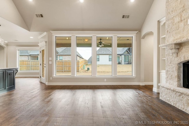 unfurnished living room featuring lofted ceiling, built in shelves, ceiling fan, a fireplace, and dark hardwood / wood-style flooring