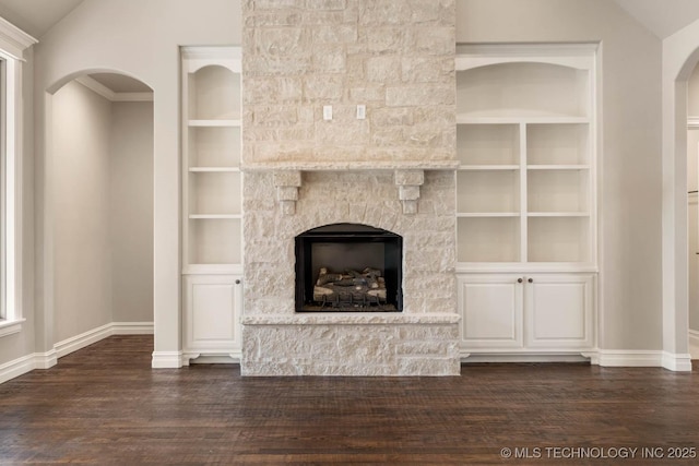 unfurnished living room featuring lofted ceiling, dark hardwood / wood-style flooring, built in features, and a fireplace