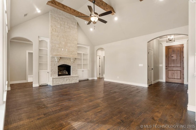 unfurnished living room with built in shelves, a stone fireplace, beamed ceiling, high vaulted ceiling, and ceiling fan with notable chandelier