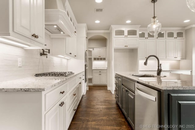 kitchen with white cabinetry, sink, light stone countertops, custom range hood, and appliances with stainless steel finishes