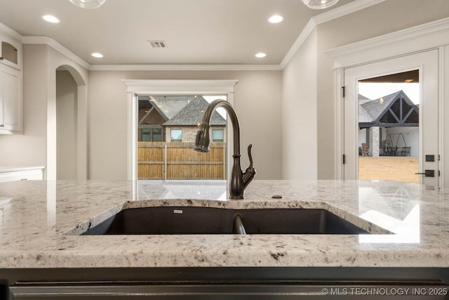 kitchen with crown molding, sink, white cabinets, and light stone countertops