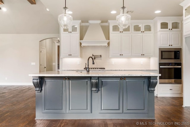 kitchen with wall oven, white cabinetry, and a kitchen island with sink