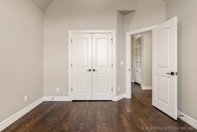 unfurnished bedroom with dark hardwood / wood-style floors, a closet, and lofted ceiling