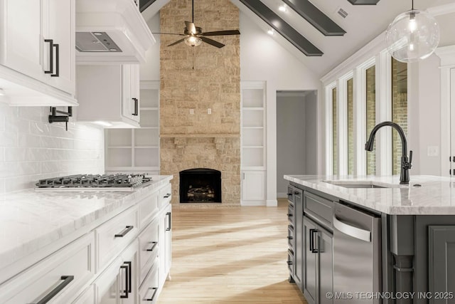 kitchen featuring white cabinets, tasteful backsplash, light stone countertops, and an island with sink