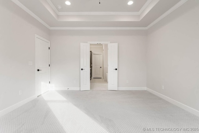 carpeted spare room with a raised ceiling and crown molding