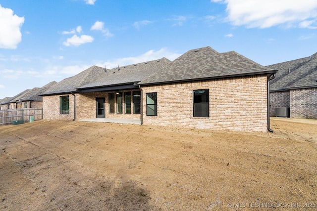 rear view of property featuring a lawn, central AC unit, and a patio area