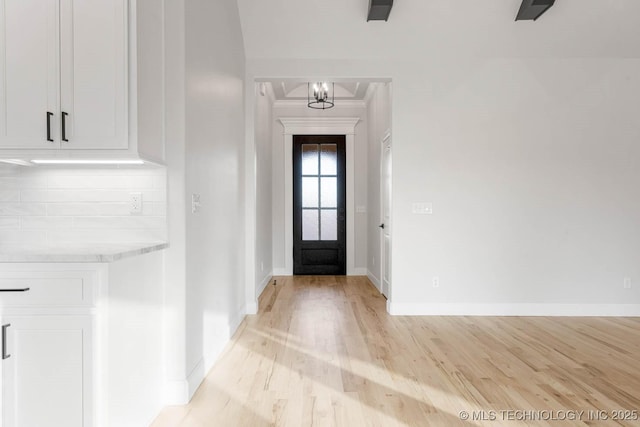 entryway with light hardwood / wood-style floors and an inviting chandelier