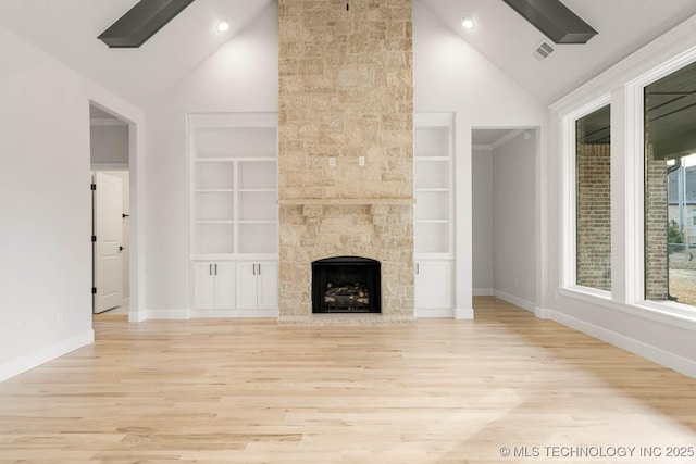 unfurnished living room featuring a stone fireplace, built in shelves, high vaulted ceiling, and light wood-type flooring