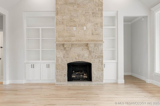 unfurnished living room featuring built in shelves, a stone fireplace, and light wood-type flooring