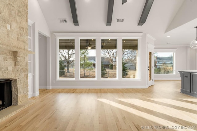 unfurnished living room with a stone fireplace, ceiling fan, light hardwood / wood-style flooring, and vaulted ceiling with beams