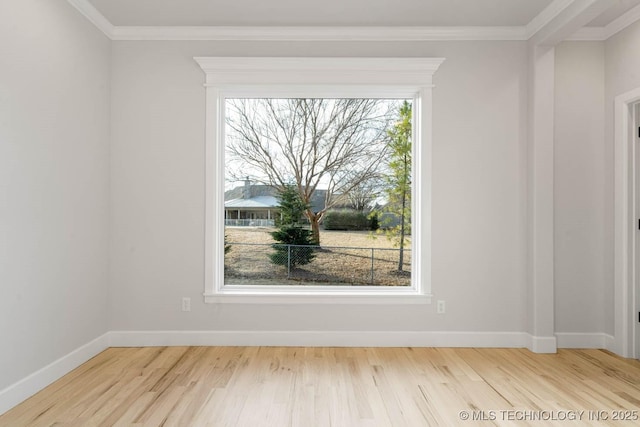 empty room featuring light wood-type flooring, crown molding, and a wealth of natural light