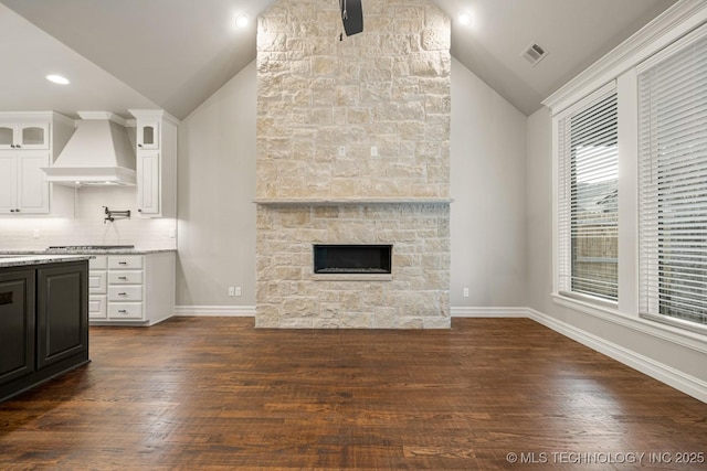 14504 E 80th St, Owasso, OK 74055 - unfurnished living room with dark wood finished floors, baseboards, visible vents, lofted ceiling, and a stone fireplace