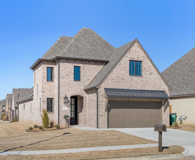 french country inspired facade with driveway, brick siding, and a shingled roof