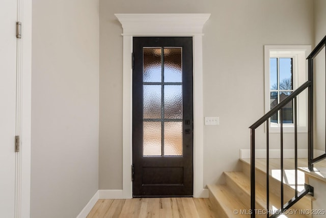 foyer entrance with light wood-type flooring, plenty of natural light, stairs, and baseboards