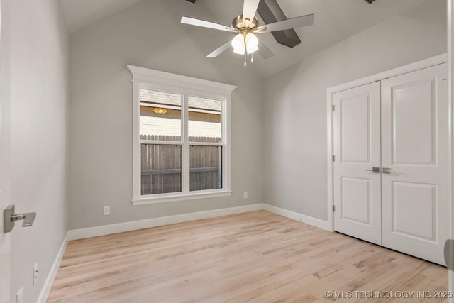 empty room with lofted ceiling, baseboards, a ceiling fan, and wood finished floors