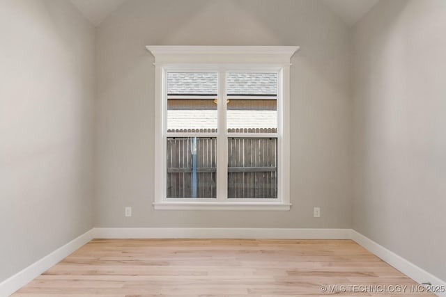 spare room featuring vaulted ceiling, wood finished floors, and baseboards