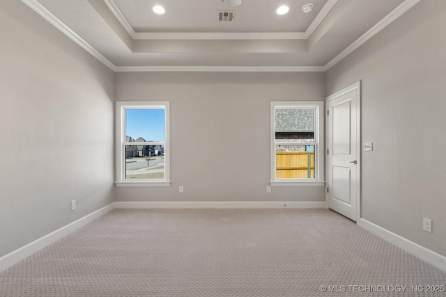 empty room with a raised ceiling, visible vents, and baseboards