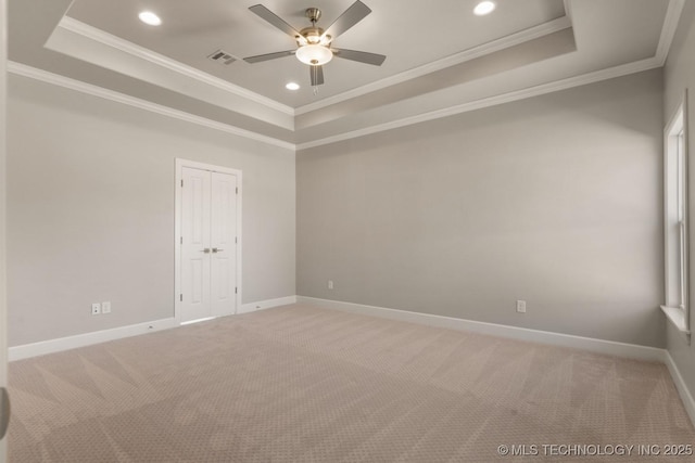 unfurnished room with a tray ceiling, visible vents, and baseboards