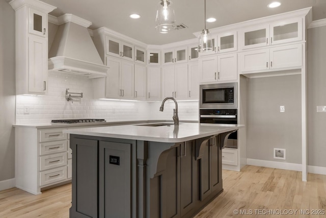 kitchen with gas stovetop, custom exhaust hood, wall oven, a sink, and built in microwave