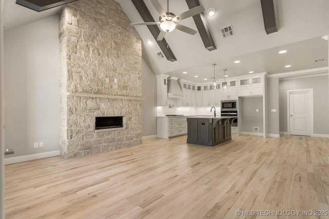 kitchen with a sink, visible vents, open floor plan, appliances with stainless steel finishes, and wall chimney range hood