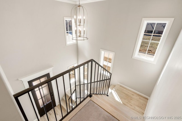 stairs featuring baseboards, a notable chandelier, and wood finished floors