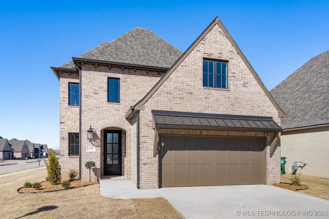 french country inspired facade with a shingled roof, brick siding, driveway, and a garage