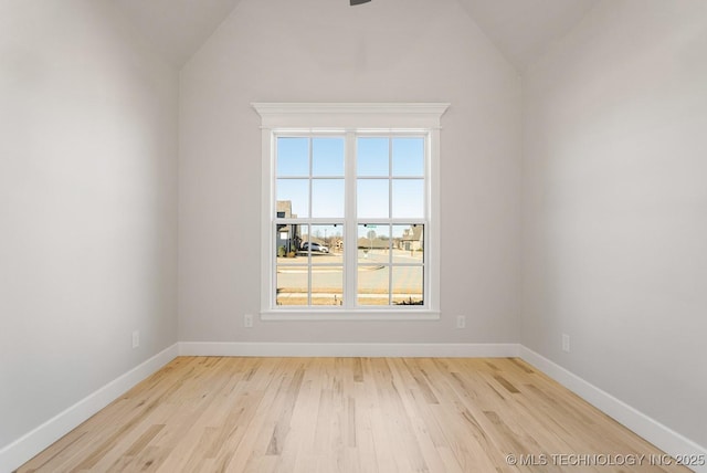 unfurnished room with vaulted ceiling, wood finished floors, and baseboards