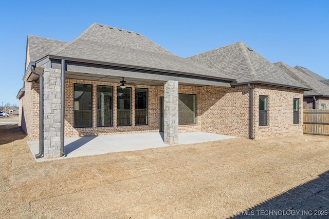 rear view of property featuring ceiling fan, a shingled roof, brick siding, stone siding, and a patio area