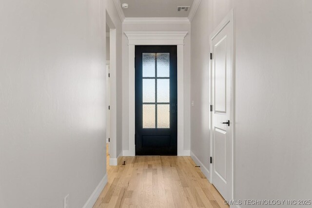 doorway featuring baseboards, visible vents, crown molding, and light wood finished floors