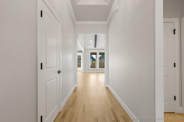 hall with light wood-style flooring, baseboards, and crown molding