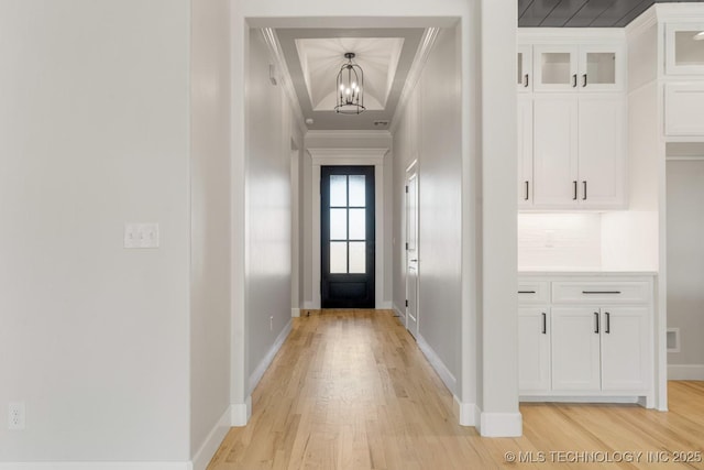 entryway with crown molding, visible vents, baseboards, light wood-style floors, and an inviting chandelier