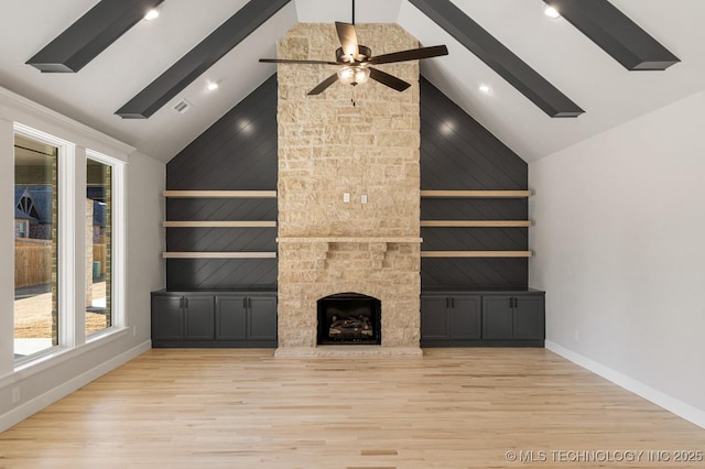 unfurnished living room with a stone fireplace, beamed ceiling, and wood finished floors