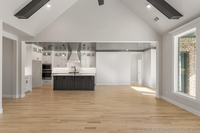 kitchen with light countertops, visible vents, stainless steel microwave, open floor plan, and white cabinetry