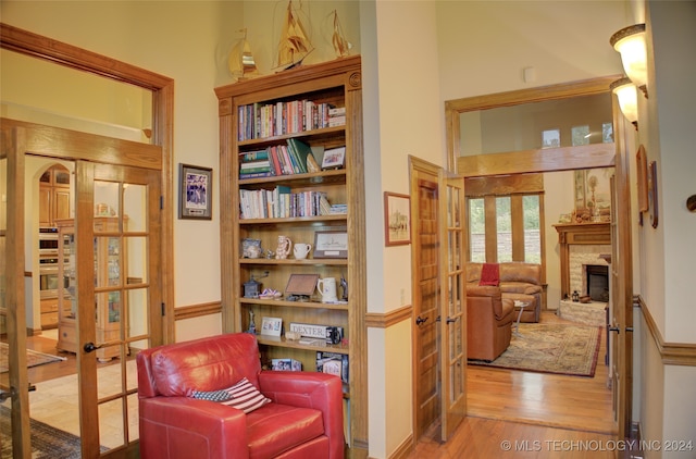 living area with light wood-type flooring, french doors, and a stone fireplace