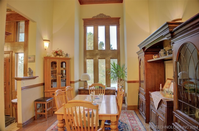 dining room with a towering ceiling and light hardwood / wood-style flooring