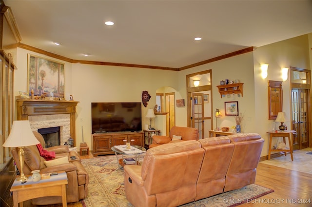 living room featuring crown molding, light wood-type flooring, and a fireplace