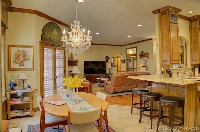 dining area featuring a chandelier, light hardwood / wood-style floors, crown molding, and sink