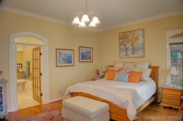 bedroom with wood-type flooring, ensuite bathroom, an inviting chandelier, and ornamental molding