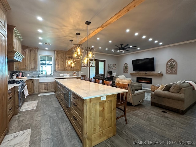 kitchen featuring high end stainless steel range oven, ceiling fan with notable chandelier, a kitchen island, hanging light fixtures, and dark hardwood / wood-style floors