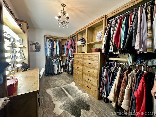 spacious closet featuring a chandelier and dark hardwood / wood-style floors