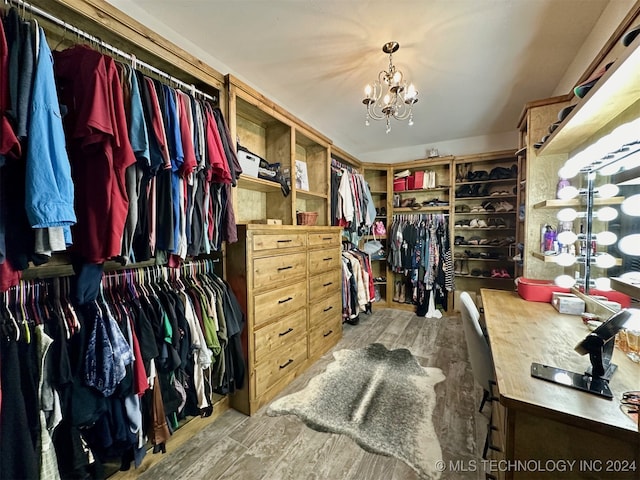 spacious closet with hardwood / wood-style floors and an inviting chandelier