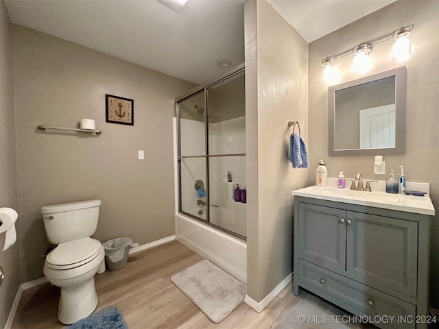 full bathroom featuring hardwood / wood-style floors, toilet, bath / shower combo with glass door, and vanity