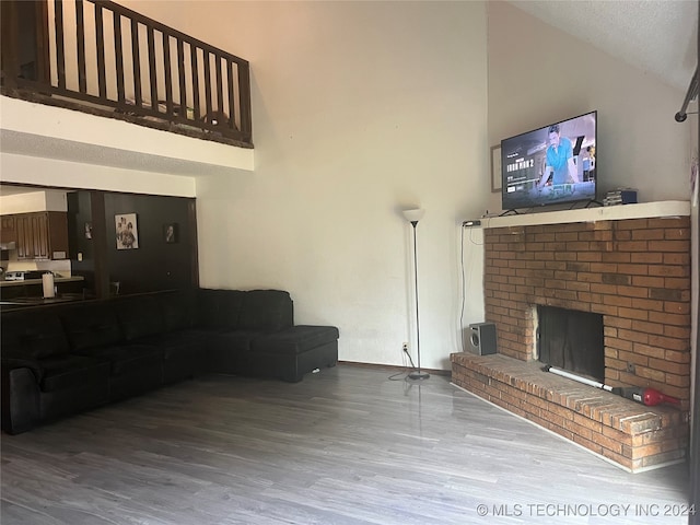 living room featuring a fireplace, high vaulted ceiling, hardwood / wood-style flooring, and a textured ceiling