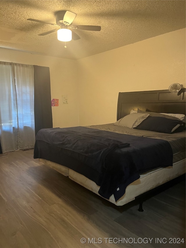 bedroom with a textured ceiling, wood-type flooring, and ceiling fan