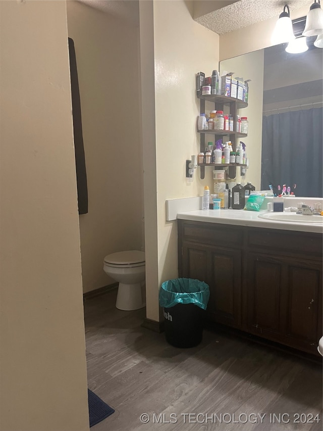 bathroom featuring a textured ceiling, vanity, toilet, and hardwood / wood-style floors