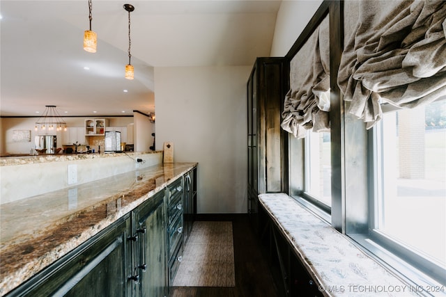 kitchen featuring hanging light fixtures, dark hardwood / wood-style floors, stainless steel fridge, and light stone counters