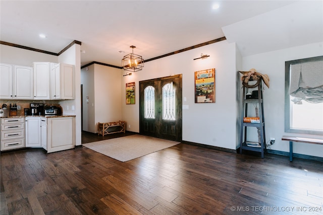 entrance foyer featuring a notable chandelier, ornamental molding, and dark wood-type flooring