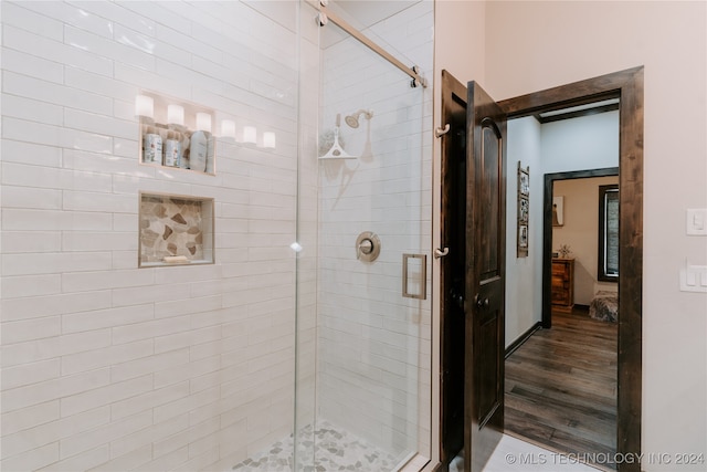 bathroom with a shower with shower door and hardwood / wood-style floors