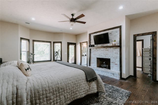 bedroom with dark hardwood / wood-style flooring, ceiling fan, and a brick fireplace