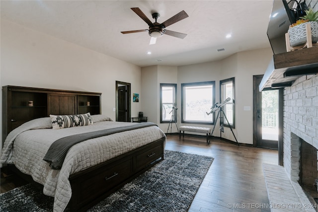 bedroom featuring a brick fireplace, ceiling fan, dark hardwood / wood-style floors, and access to exterior